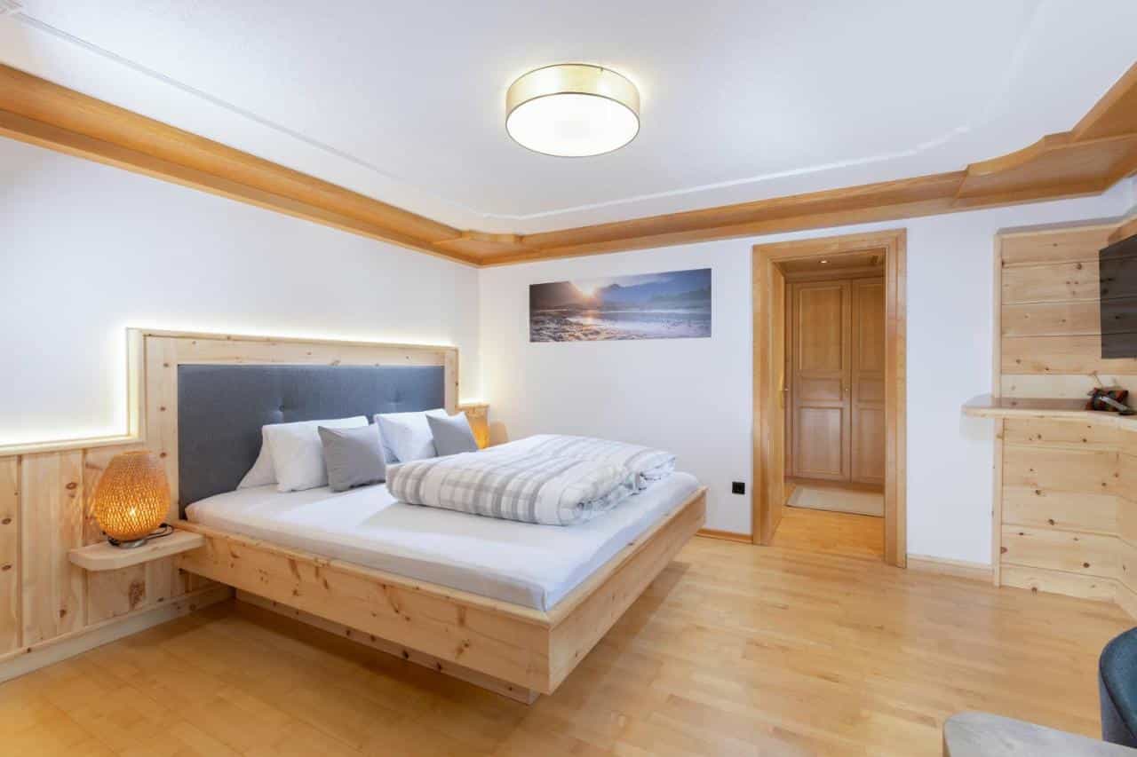 Bedroom with light wood platform bed, gray headboard, and wicker lamp in a modern alpine style.