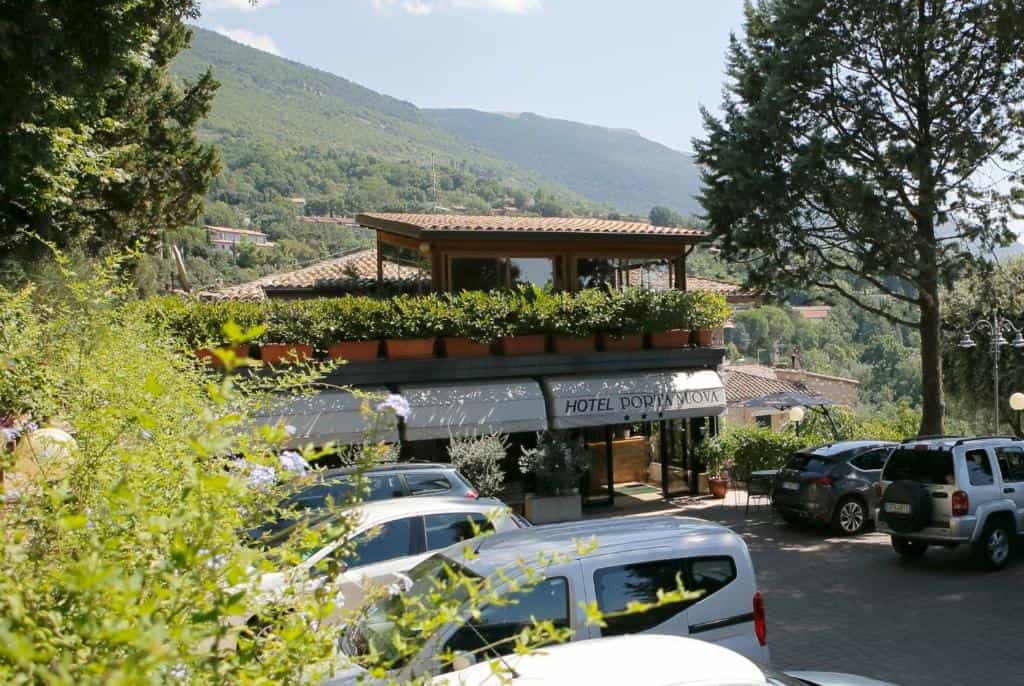 Hotel Porta Nuova entrance with parking lot and lush green mountains in background
