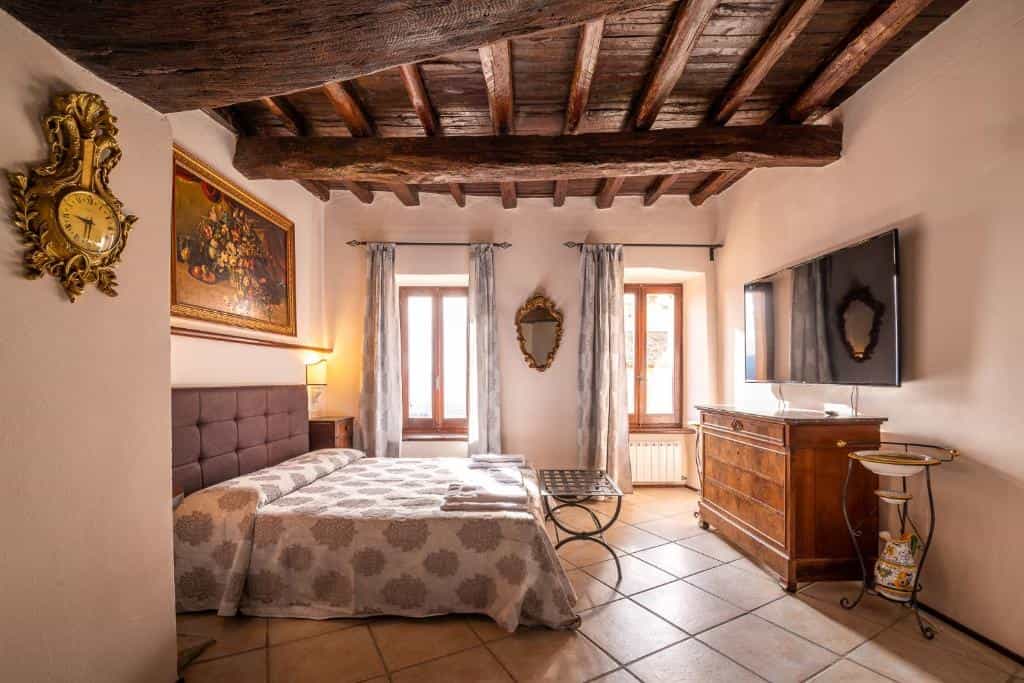 Hotel room with exposed wood beams, patterned bedding, and antique furniture at HOTEL TREVI Palazzo Natalini.