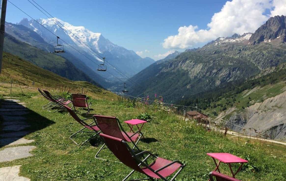 Lounge chairs on a grassy alpine slope overlooking the Chamonix valley and Mont Blanc massif.