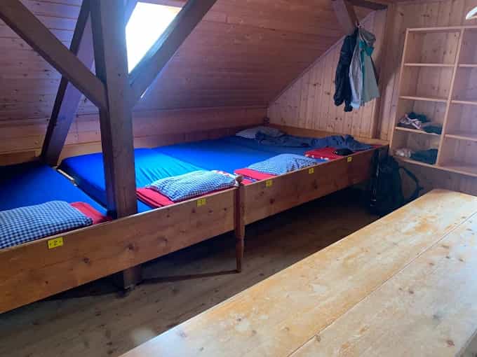 Wooden bunk room with blue mattresses, pillows, and a long wooden table in Gleiwitzer Hütte.