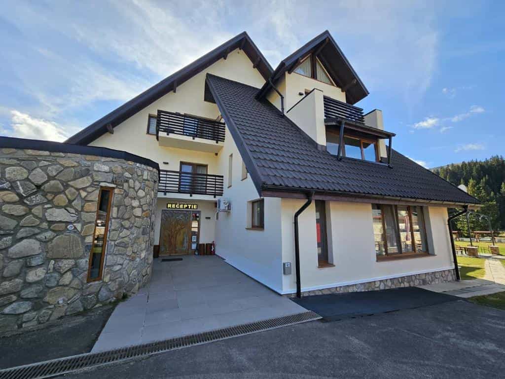 Two-story building with stone facade section and "RECEPTIE" sign under bright sky.