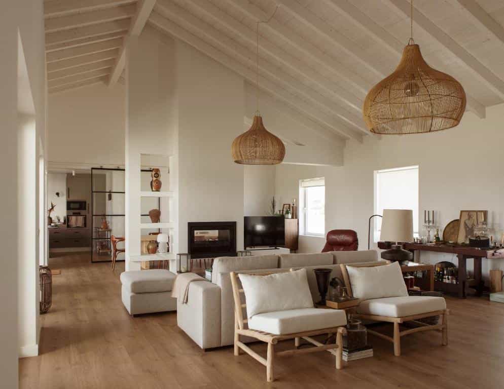 Modern living room with high vaulted ceilings, rattan pendant lights, and neutral furniture.
