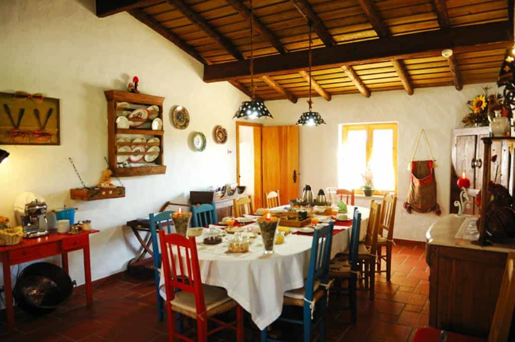 Dining room with a long table, wooden ceiling beams, and rustic decor in a traditional home.