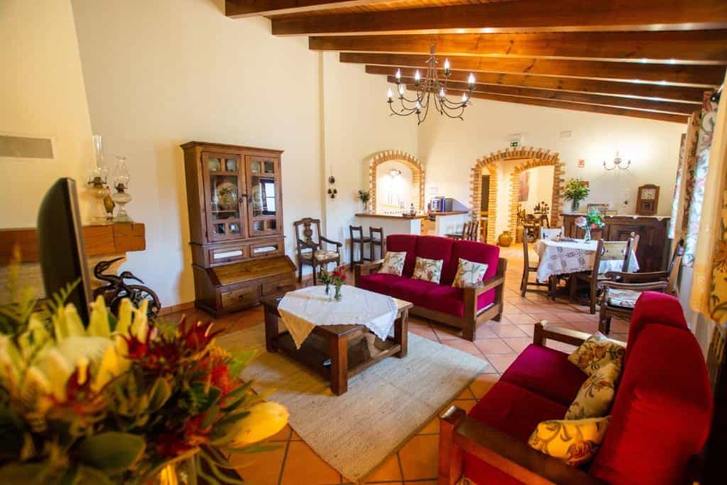 Rustic living room with red sofas, wooden furniture, and exposed ceiling beams.