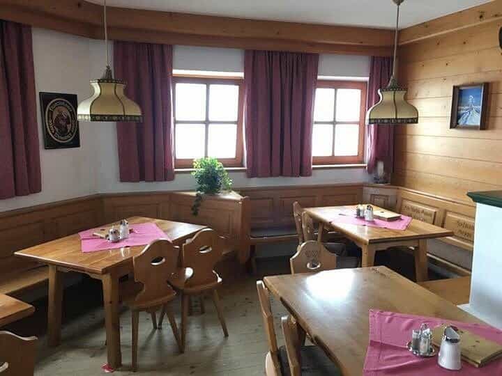 Rustic wooden dining room with tables, chairs, and bench seating in an alpine-style interior.