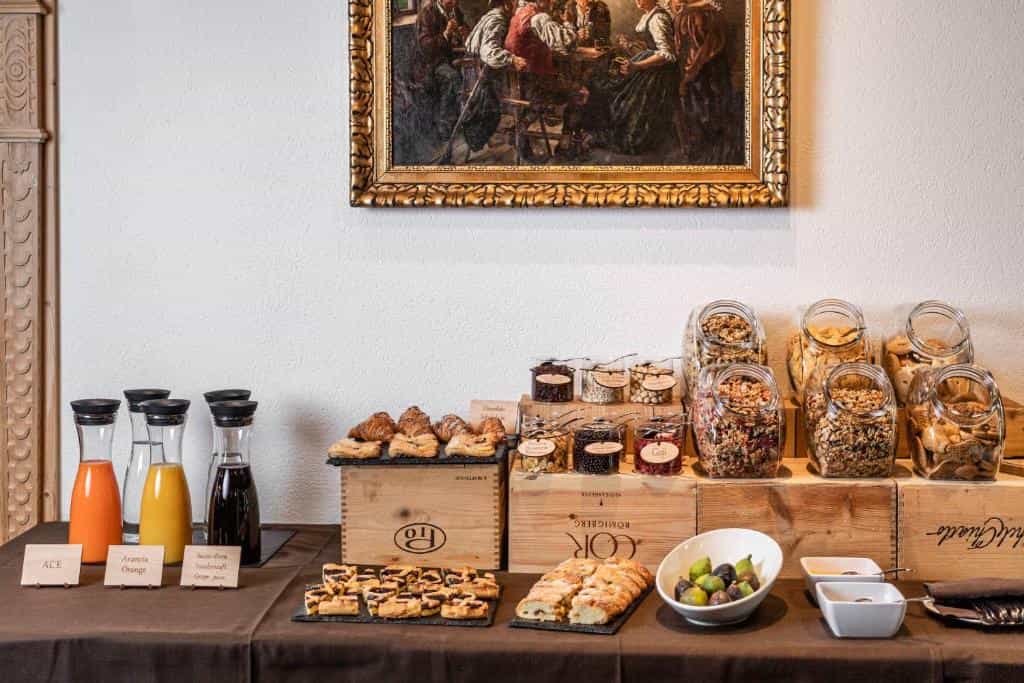 Breakfast buffet with juices, pastries, granola in glass jars, and fresh figs on a table.