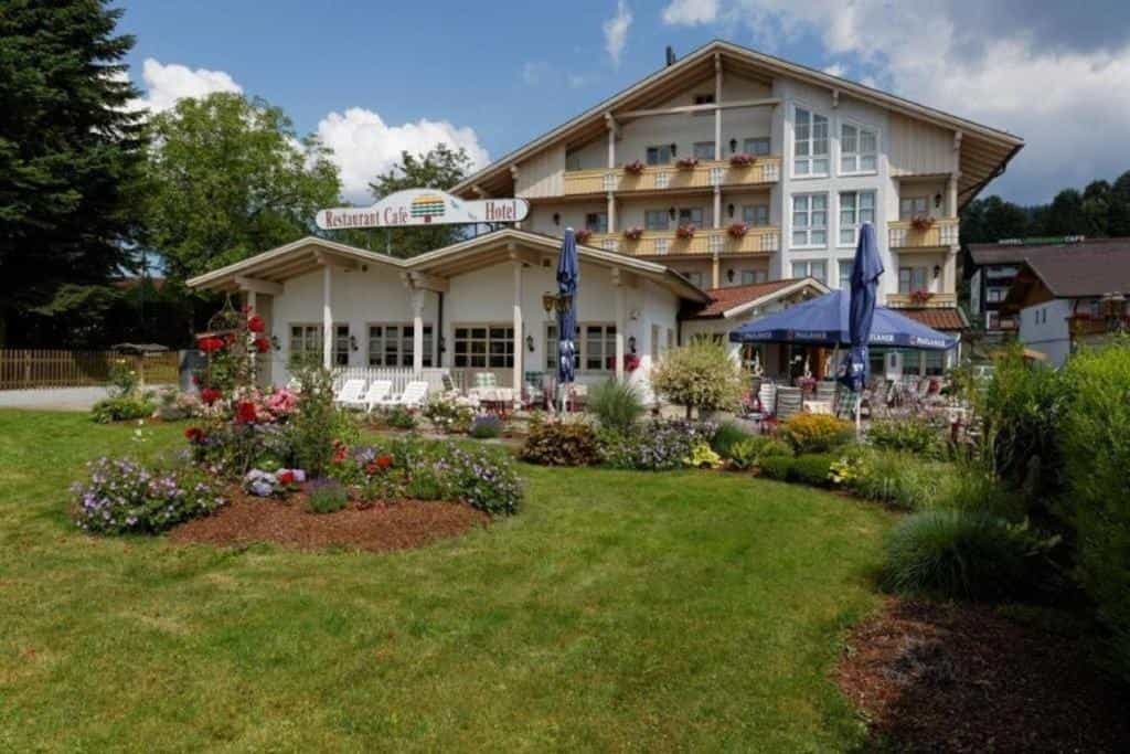 Hotel and Restaurant Café with green lawn and colorful flower beds in Bodenmais