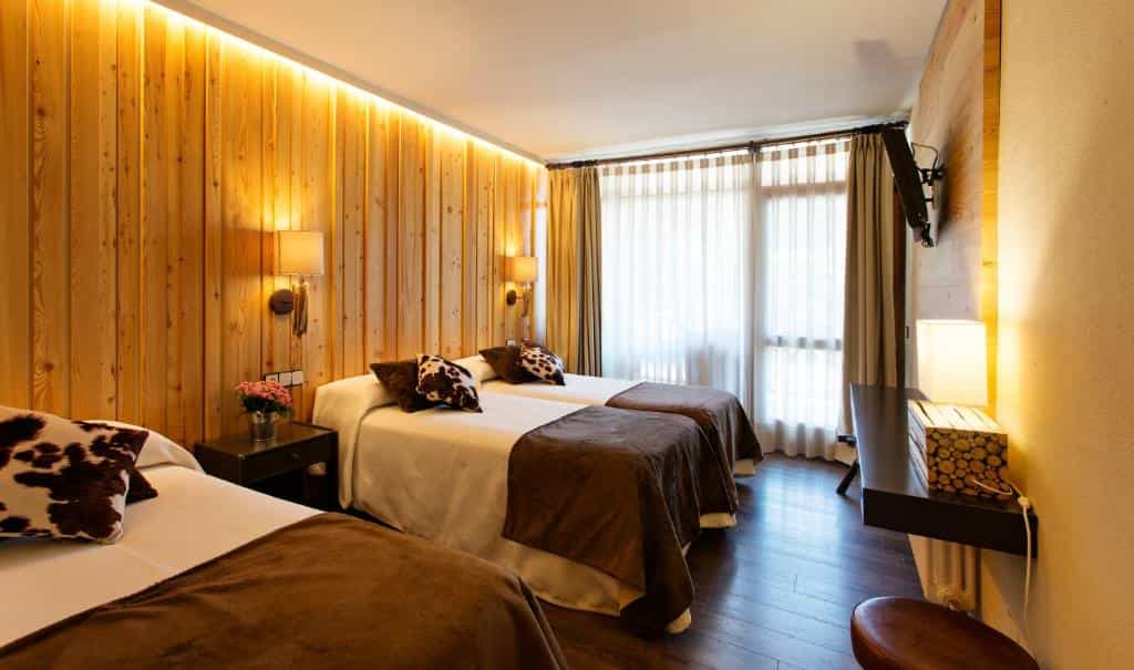 Triple hotel room with wood paneling, brown bedding, and cow print pillows in Hotel La Coma.