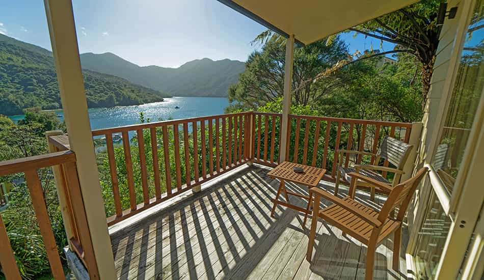 Balcony with wooden chairs and table overlooking water and mountains at Punga Cove
