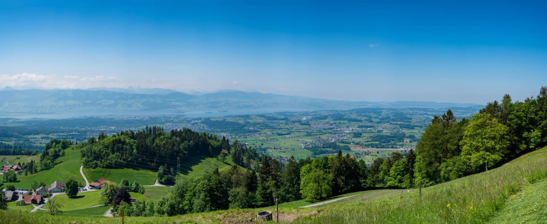 View from St. Gallenkappel towards Lake Zurich, green hills, and distant mountains.