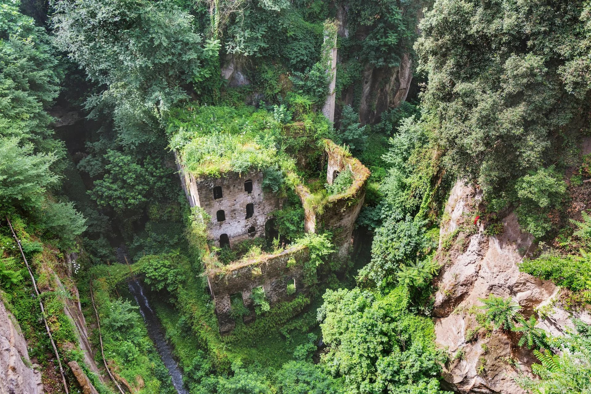 Ruins of Valle dei Mulini in Sorrento overgrown with lush green vegetation in a deep gorge.