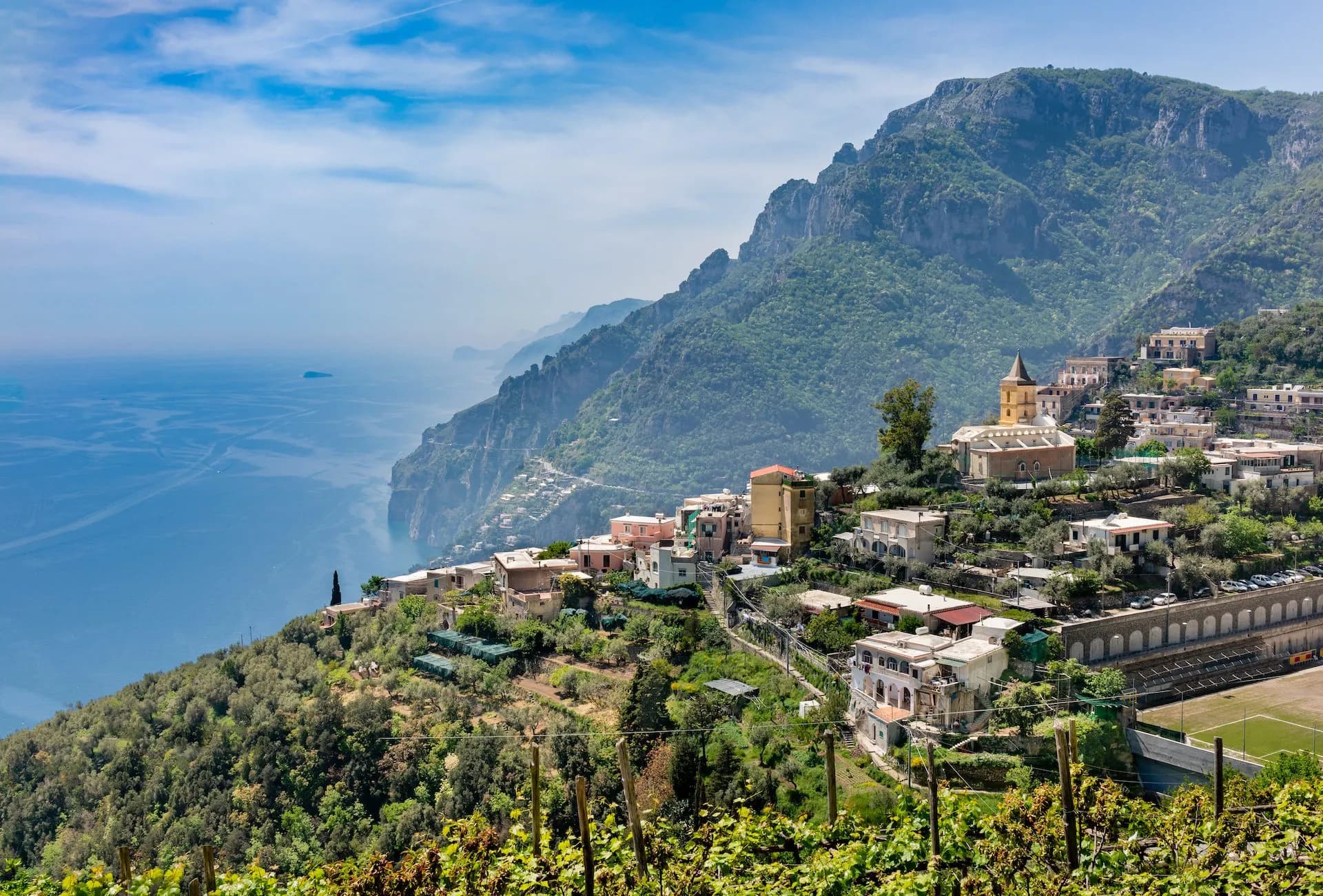 Vineyard overlooking Montepertuso village on steep green mountainside above the sea.