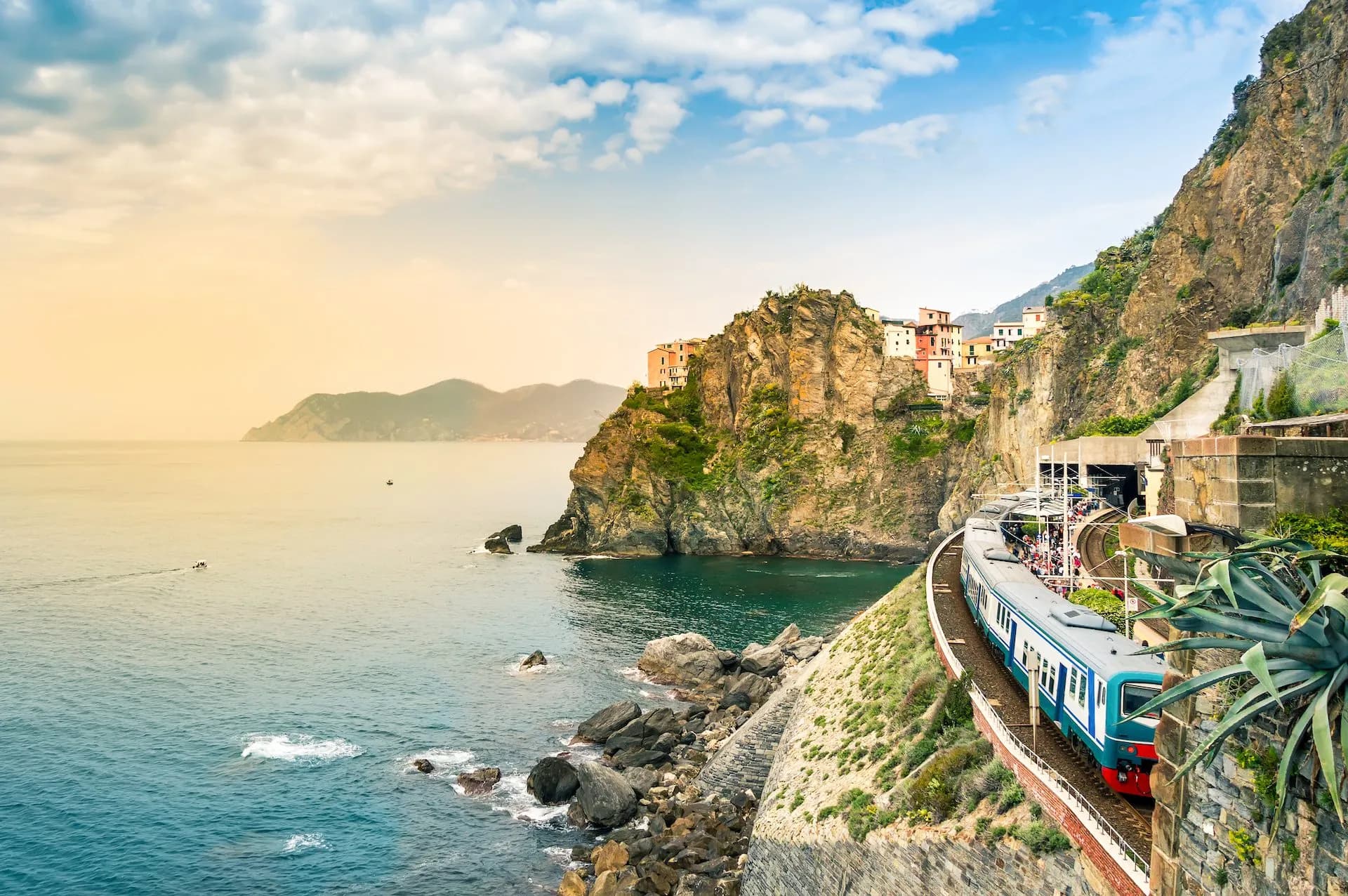 Train arriving at Manarola station carved into the cliffside overlooking the Mediterranean Sea.