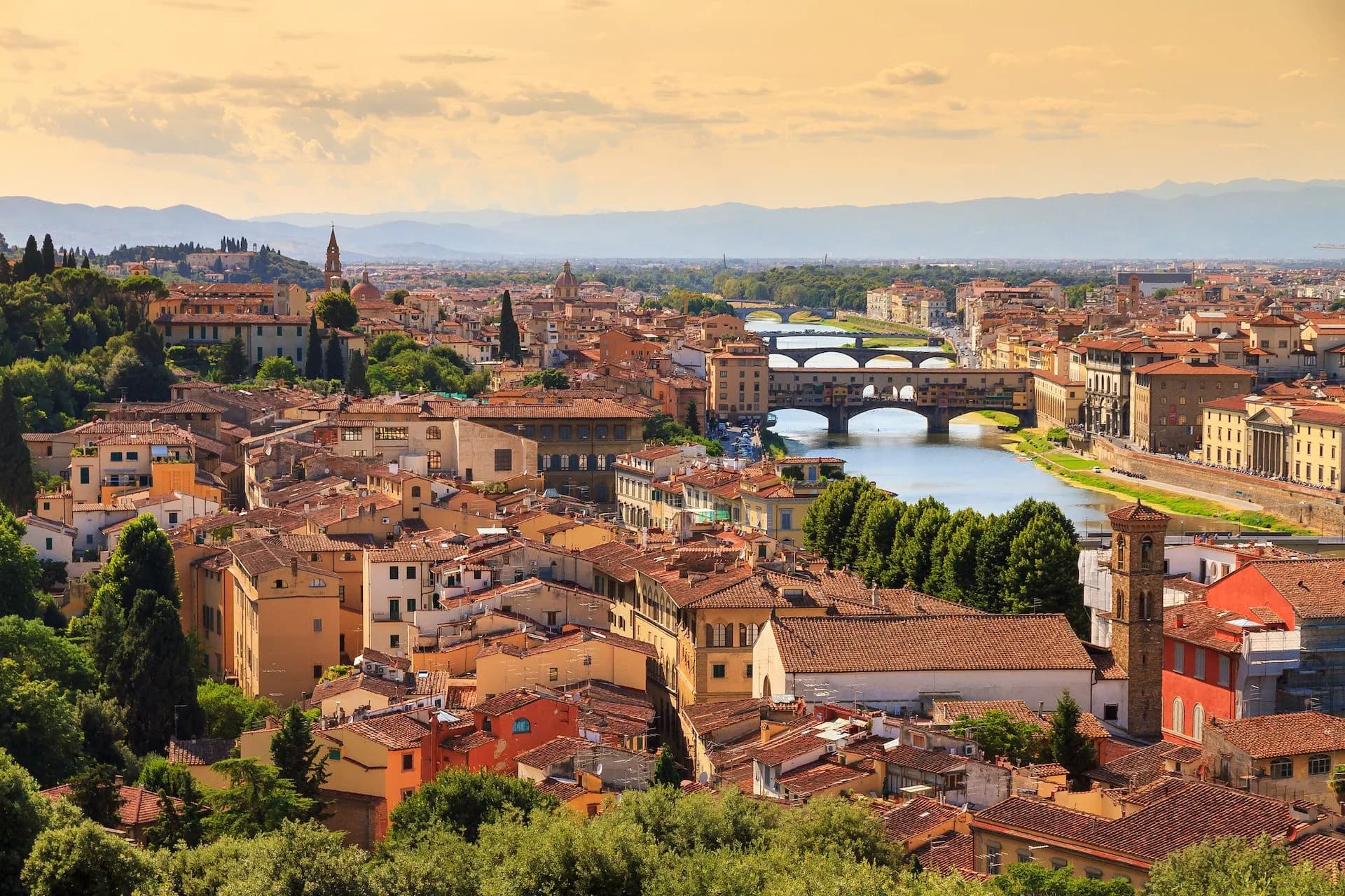 Florence cityscape with Ponte Vecchio bridge over the Arno River and distant mountains