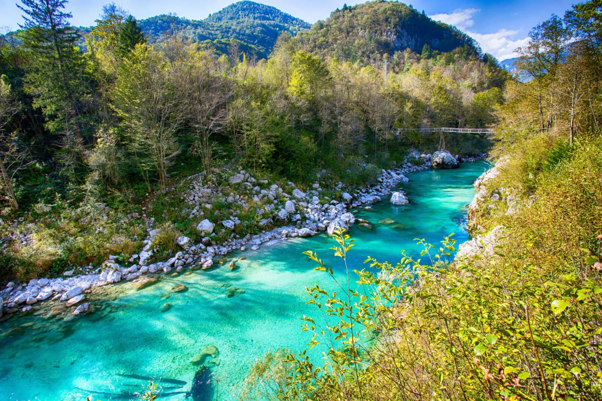 Turquoise Soca River flowing through a rocky gorge with lush green mountains in Slovenia