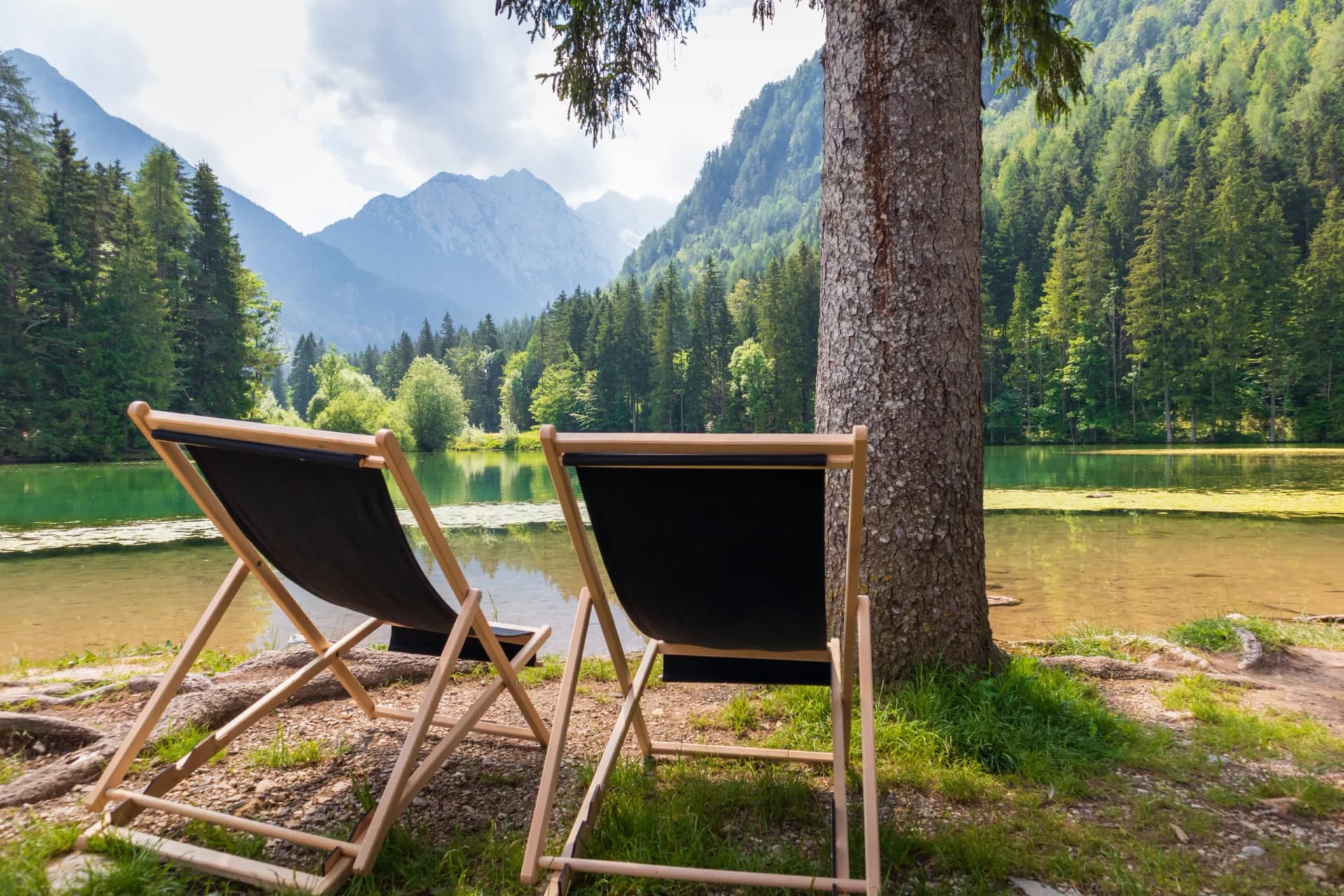 Two empty deck chairs facing Plansar Lake in Jezersko, Kamnik-Savinja Alps.