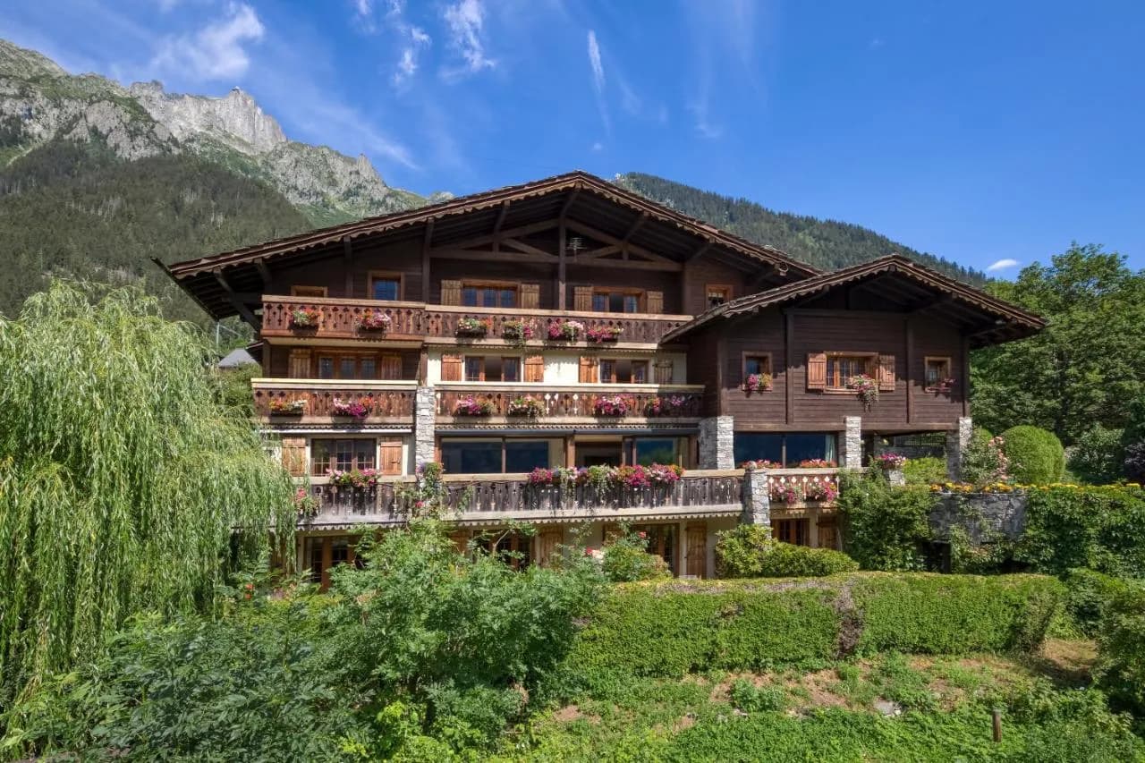 Chalet-Hotel du Bois in a lush green setting with steep mountains under a blue sky.