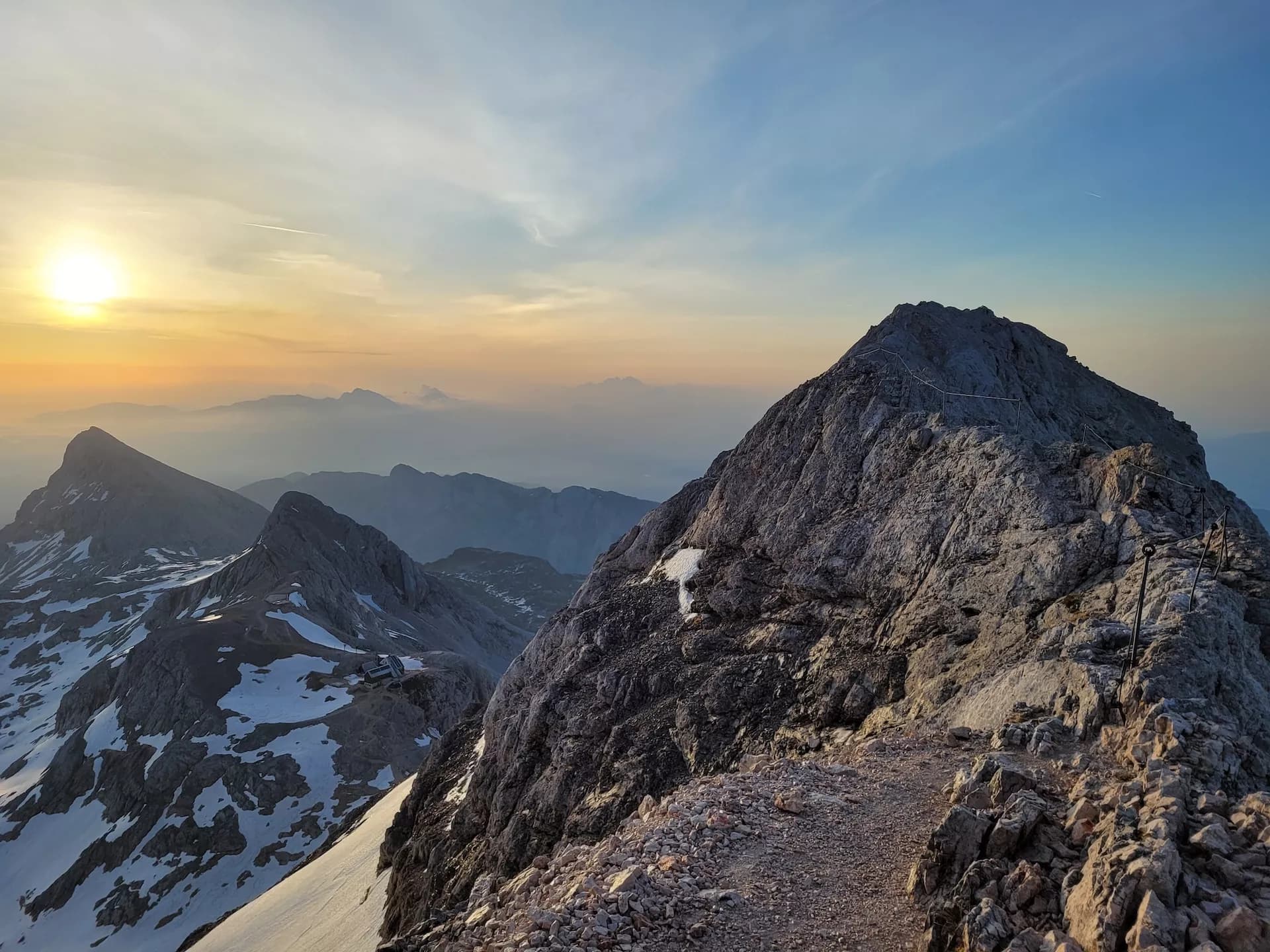 Hiking along the exposed Triglav ridge with via ferrata cables at sunrise.