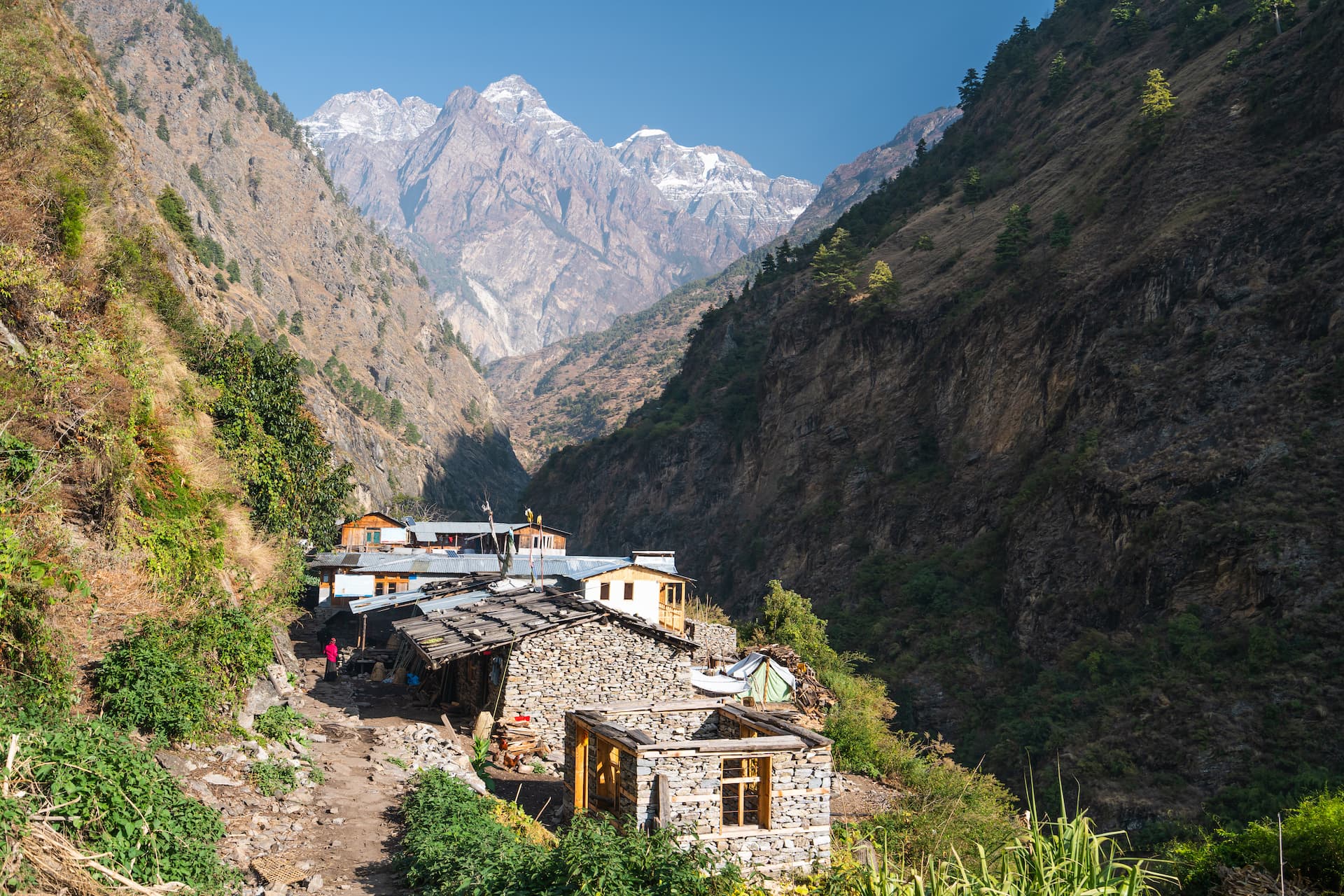 Stone houses in Deng village nestled in a deep valley below snow-capped Himalayan mountains.