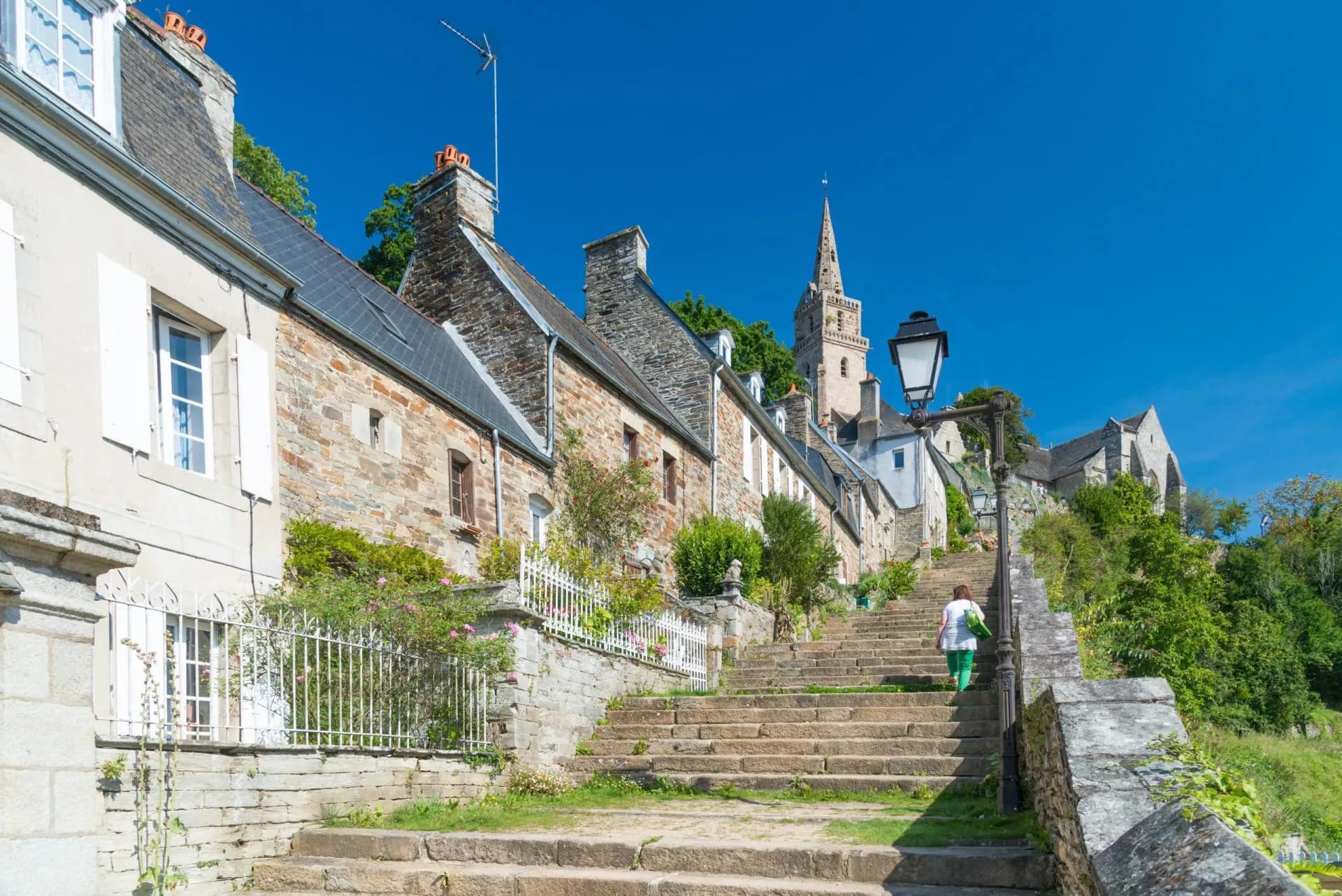 Stone staircase leading up past historic houses toward a church spire in Lannion.