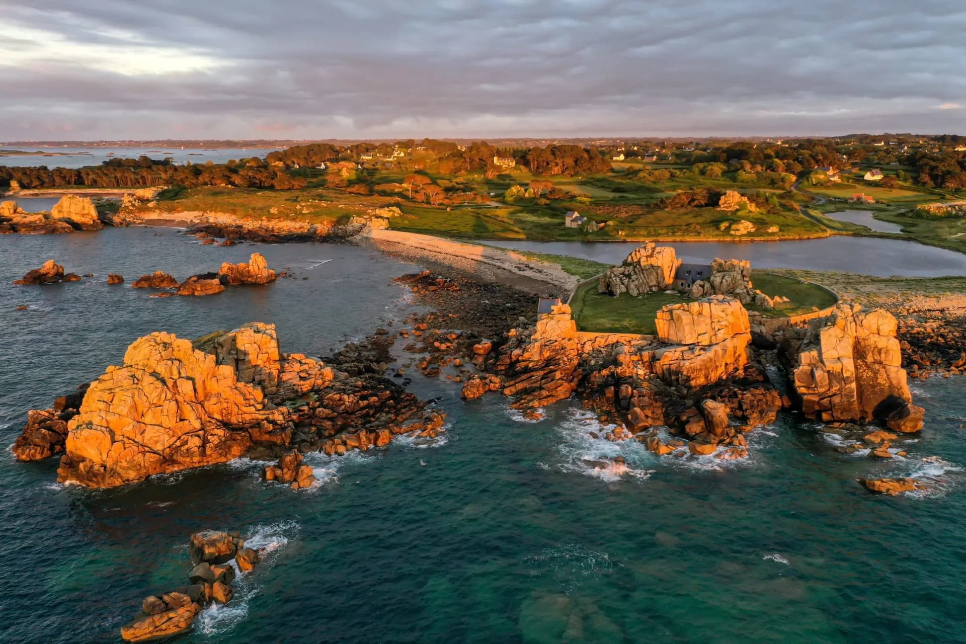 Rocky coastline of Plougrescant with orange-lit granite formations at sunset