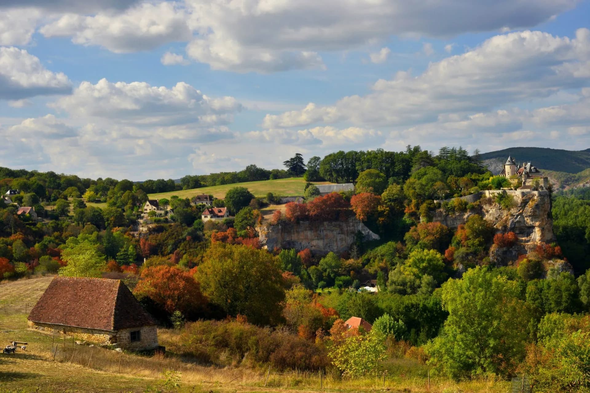 Chateau perched on cliff above village and autumn foliage near La Cave.