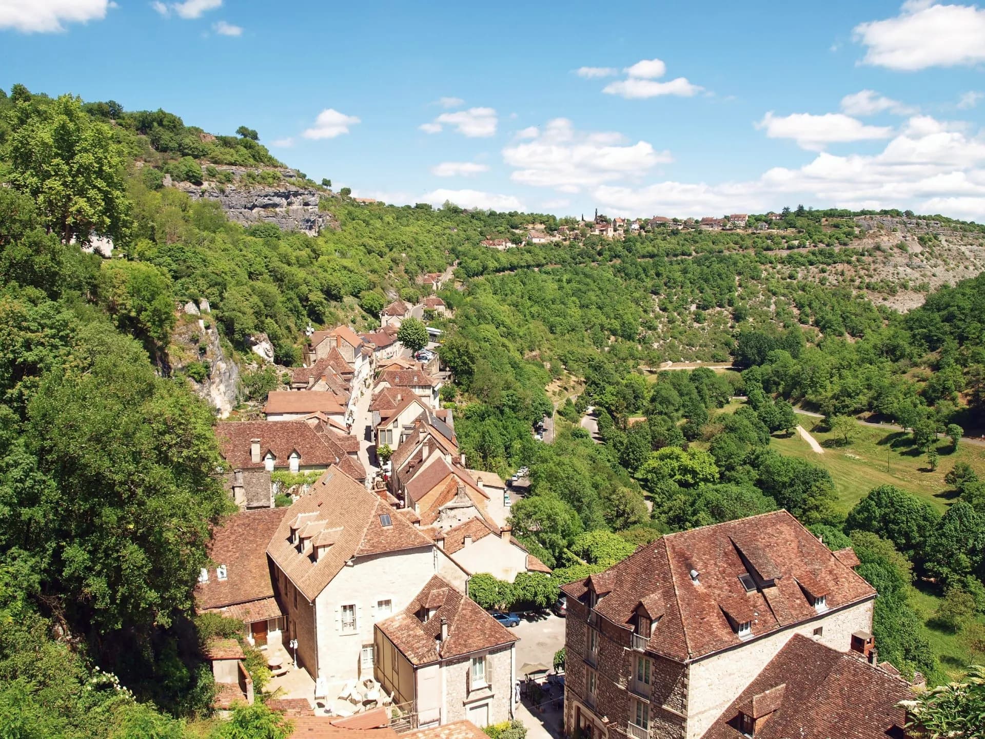 Village houses with terracotta roofs nestled in a lush, green valley near Rocamadour.