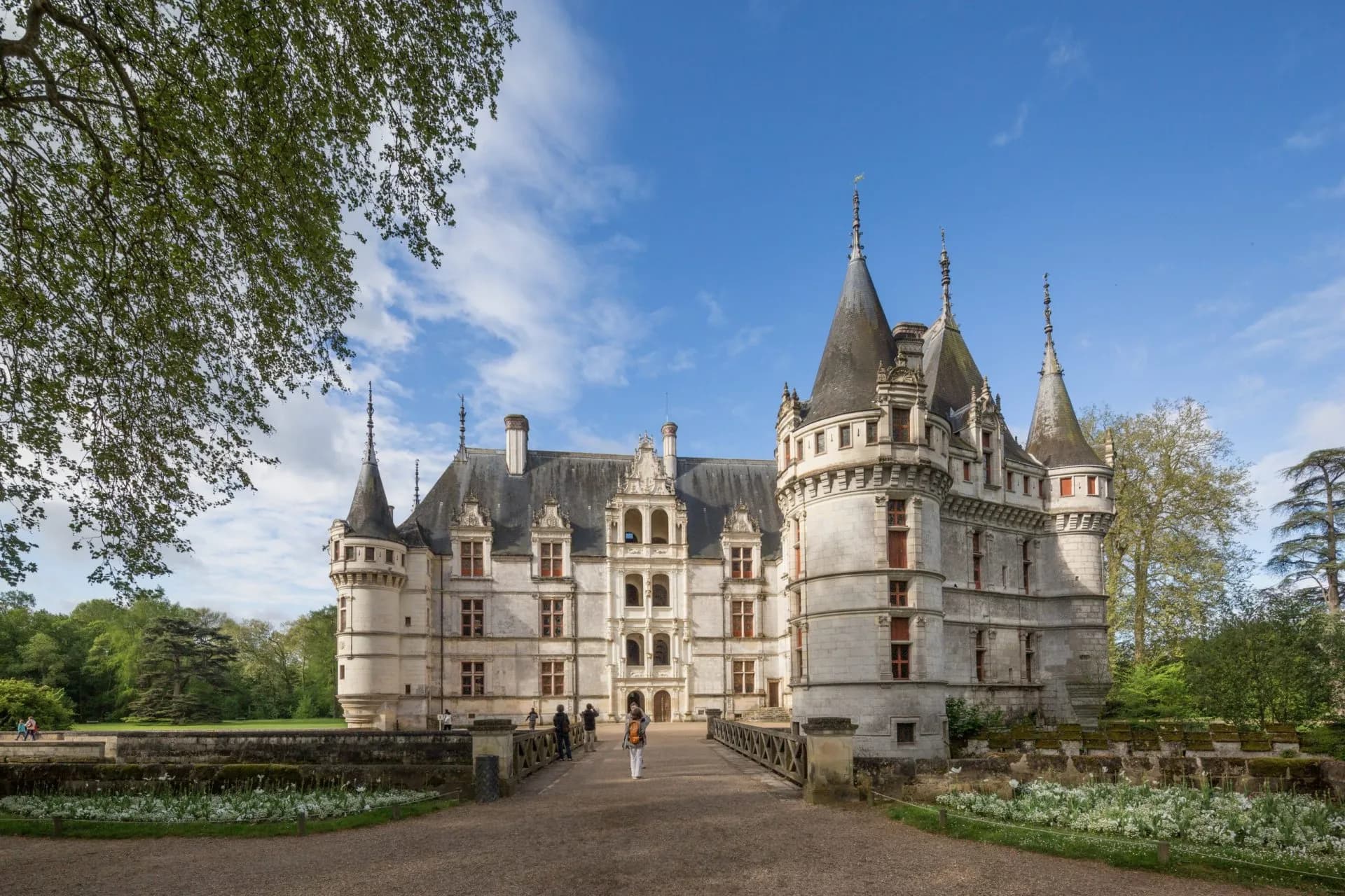 Château d'Azay-le-Rideau with turrets, stone facade, and green parkland under blue sky.