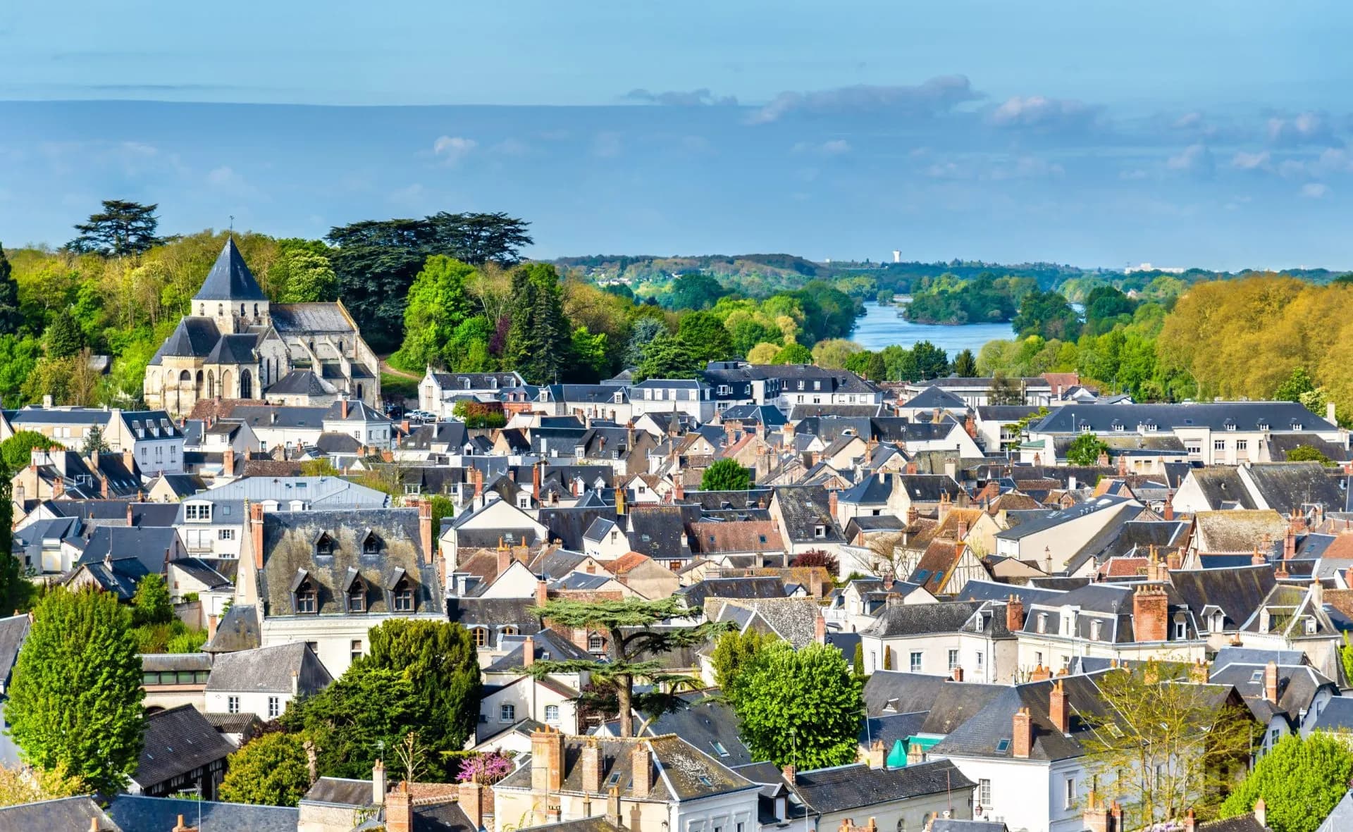 Rooftops of Amboise town with church and river in background under blue sky