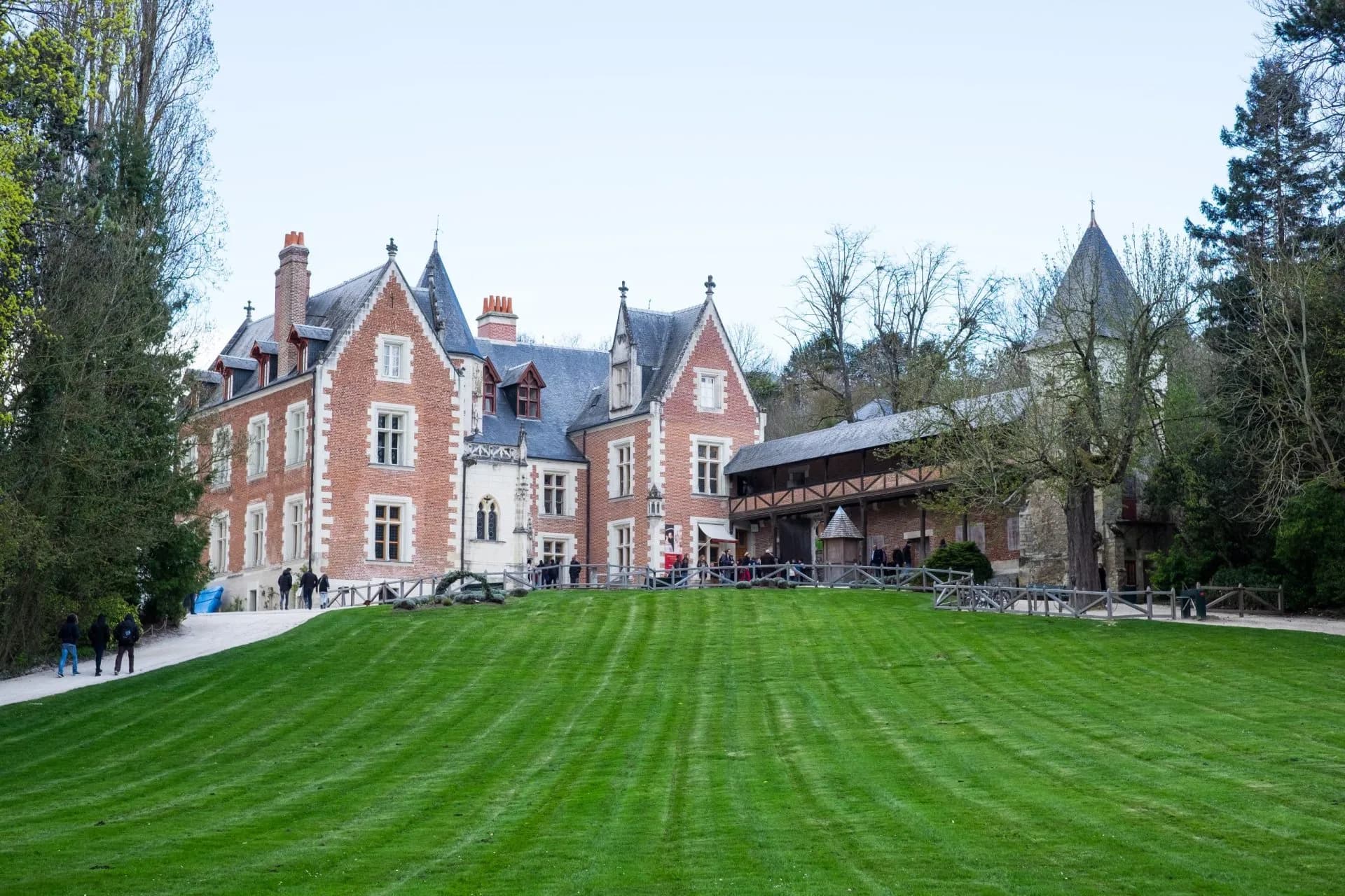 Chateau du Clos Lucé with manicured green lawn and surrounding trees.