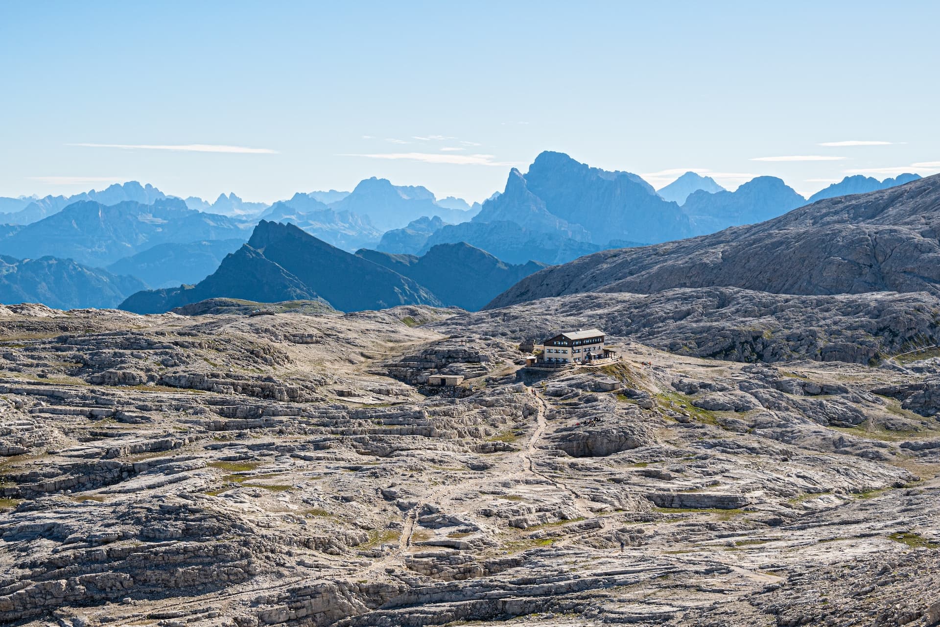 Mountain hut on rocky San Martino Plateau with layers of blue mountains in background