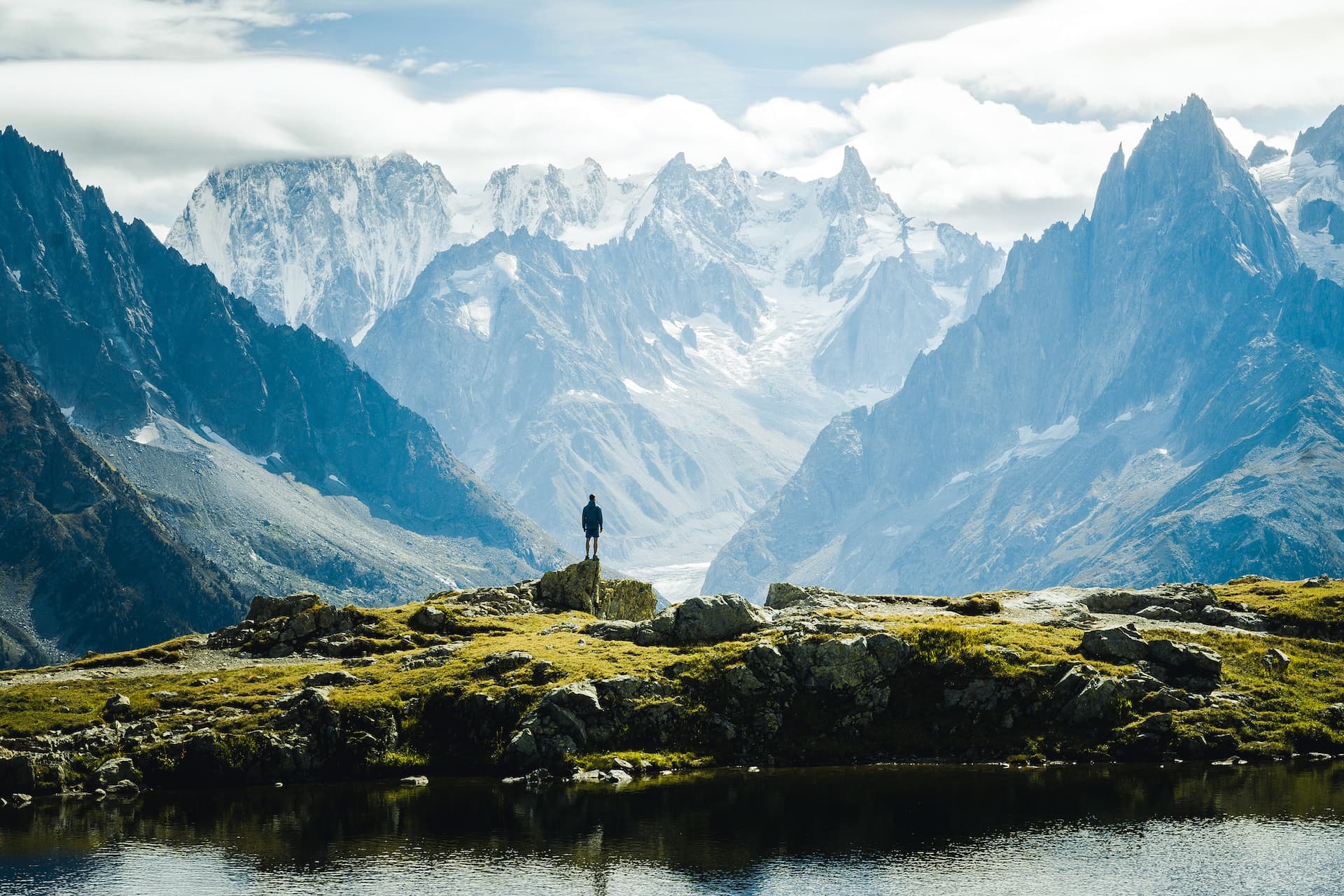 Hiker posing above Lac Blanc with snowy alpine mountains above Chamonix.