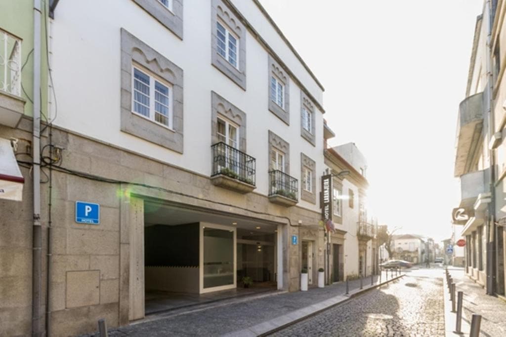 Hotel Laranjeira entrance with parking on a sunny cobblestone street in a historic town.