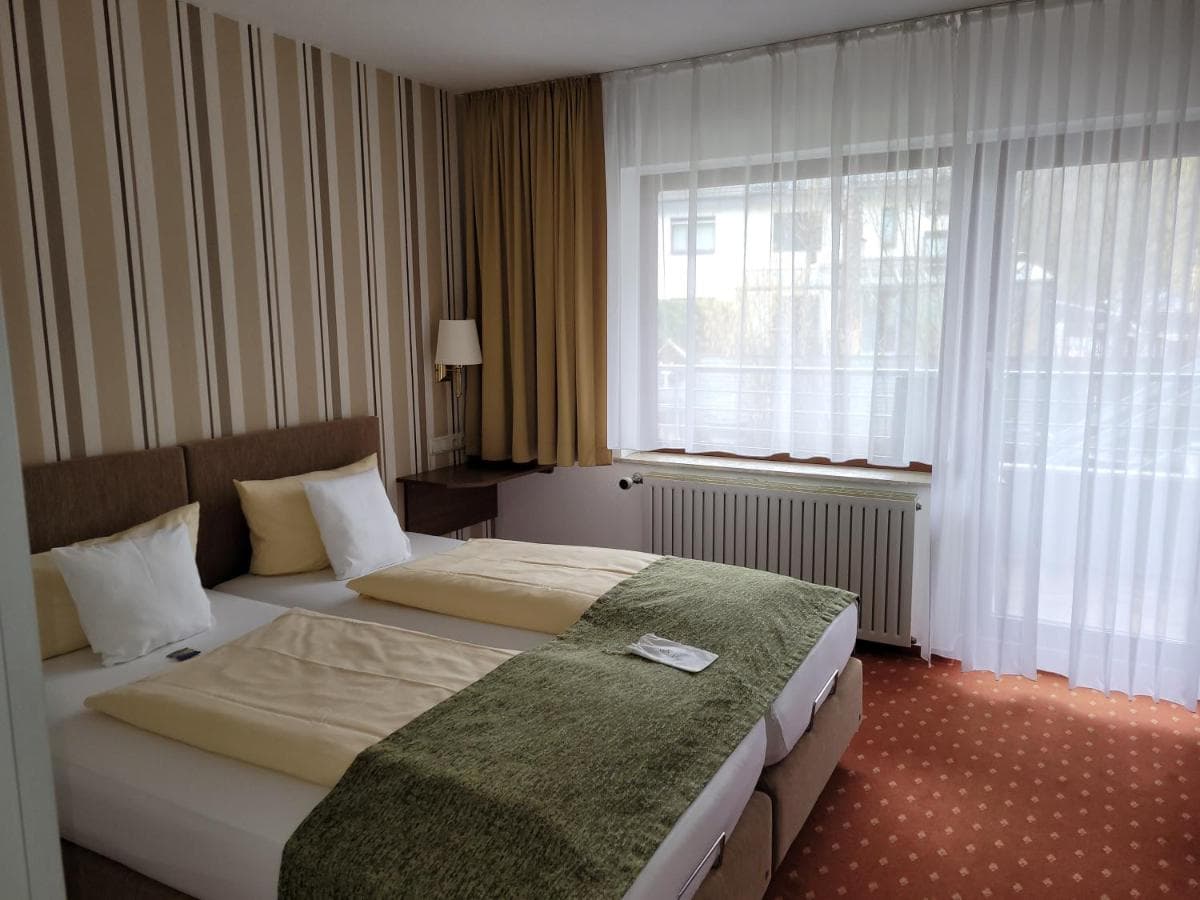 Twin beds with yellow and white linens in a hotel room at Kurparkhotel Gemünd.
