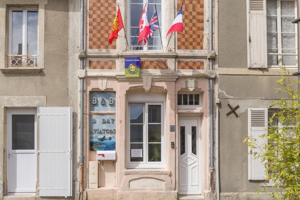 B&B entrance with D-Day Aviators sign, flags of Belgium, Canada, UK, and France.