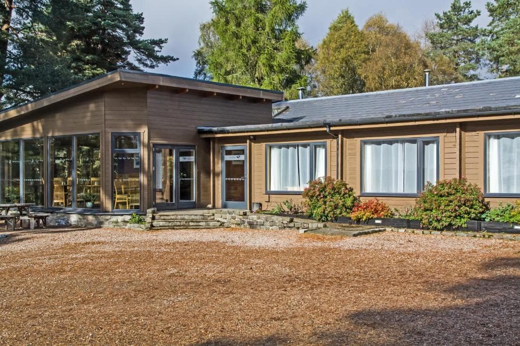 Old Pines Hotel and Restaurant building with wood siding surrounded by pine trees and wood chip ground cover.