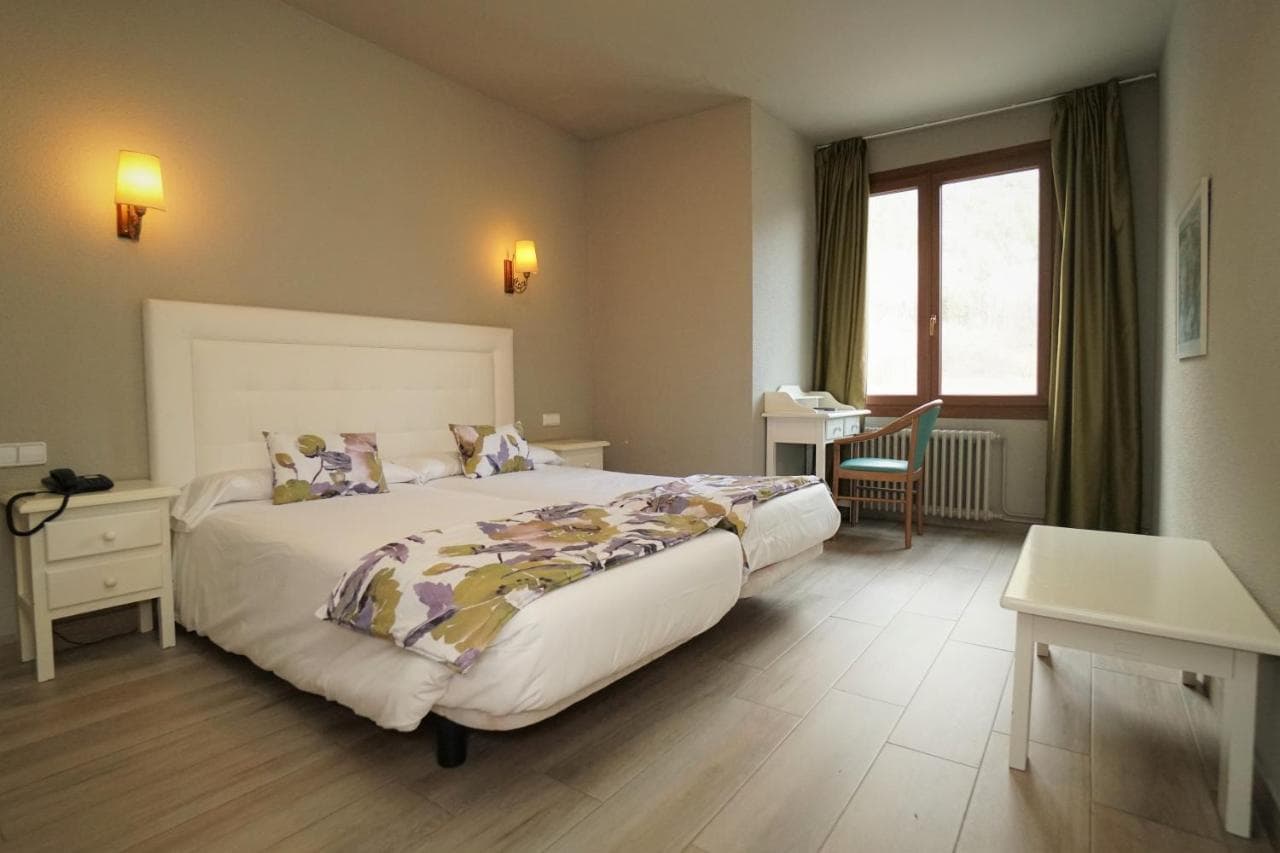 Hotel room with twin beds, white headboard, and floral throw at El Pradet.