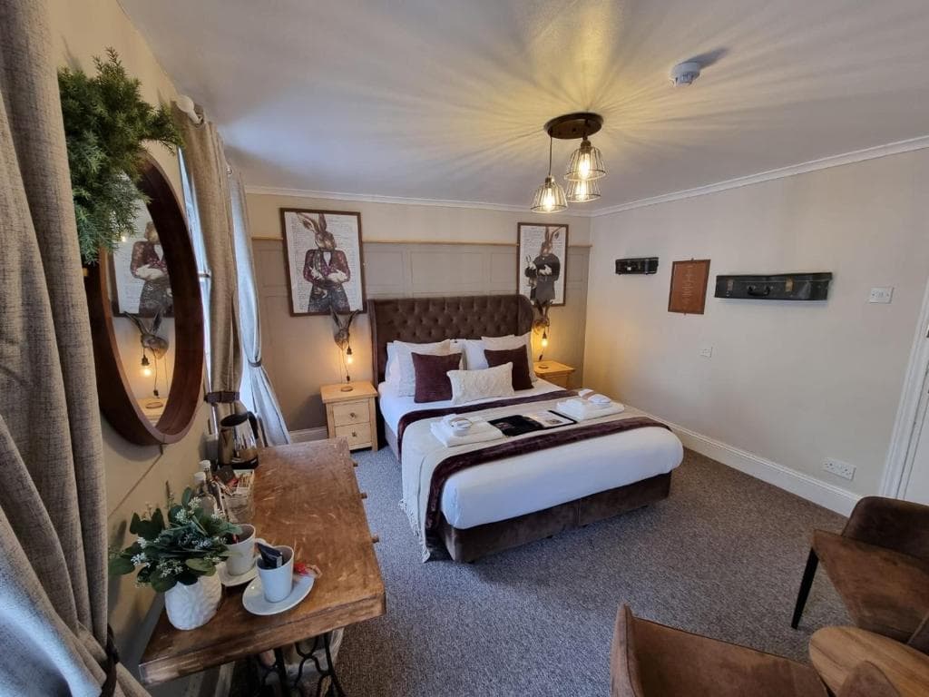 Cozy hotel bedroom with tufted headboard, rabbit artwork, and wooden console table.