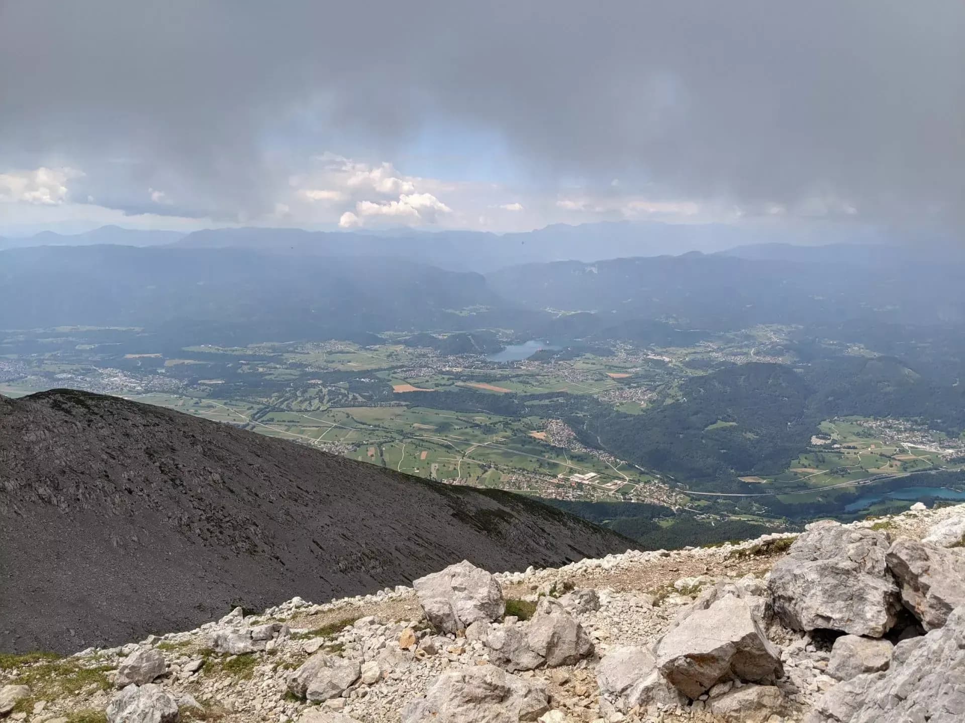 Hiking viewpoint overlooking a green valley and distant mountains under a cloudy sky.