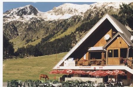 Chalet du Clot restaurant with outdoor seating below snow-capped mountains.