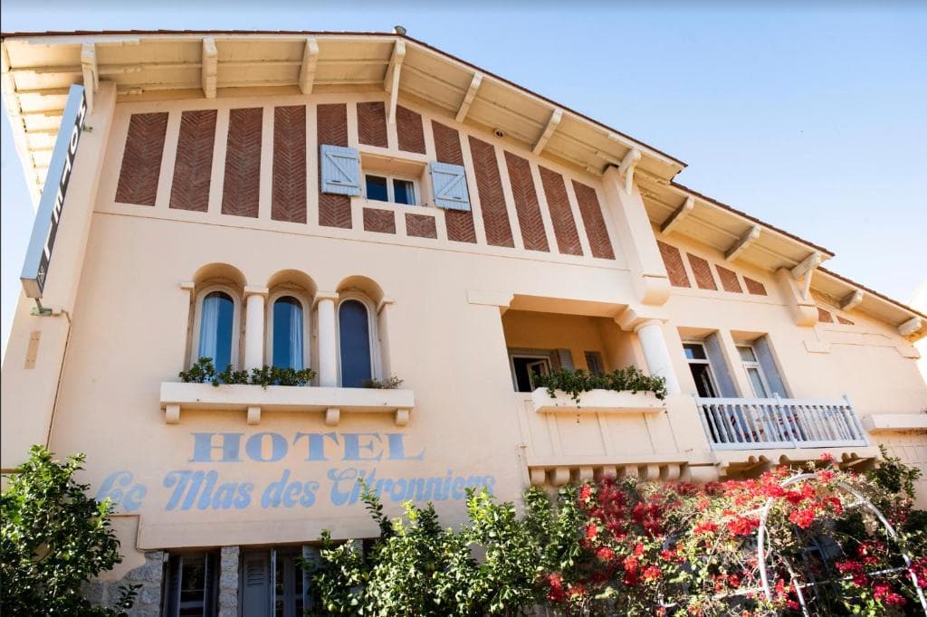 Hotel Le Mas des Citronniers building facade with arched windows and red flowering vines