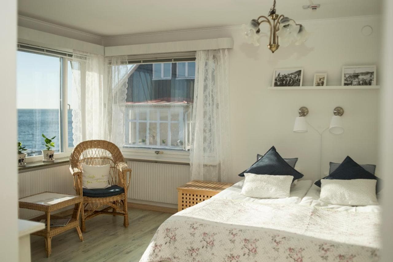 Bright bedroom with wicker chair, twin beds, and sea view from window at Pensionat Strandgården.
