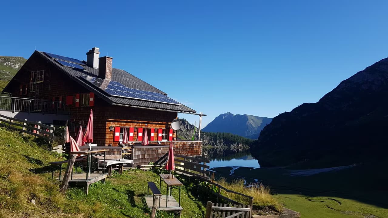 Tappenkarseehütte alpine mountain hut with outdoor seating overlooking a lake and mountains.