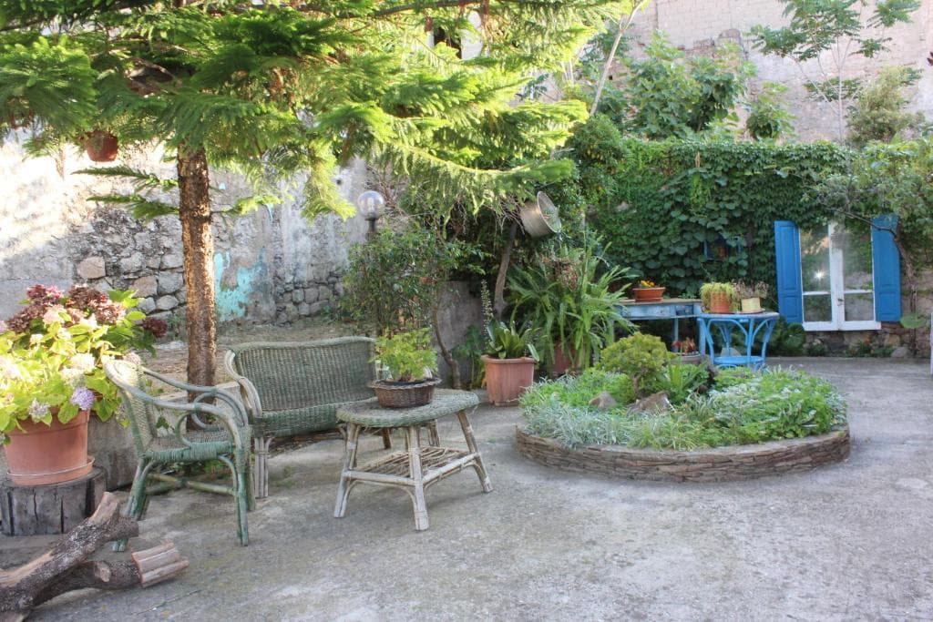 Lush garden patio with wicker furniture, potted plants, and stone planter near San Francesco.