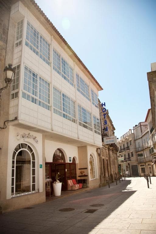 Hotel Eli Mar building facade with enclosed balconies on a sunny, narrow European street.