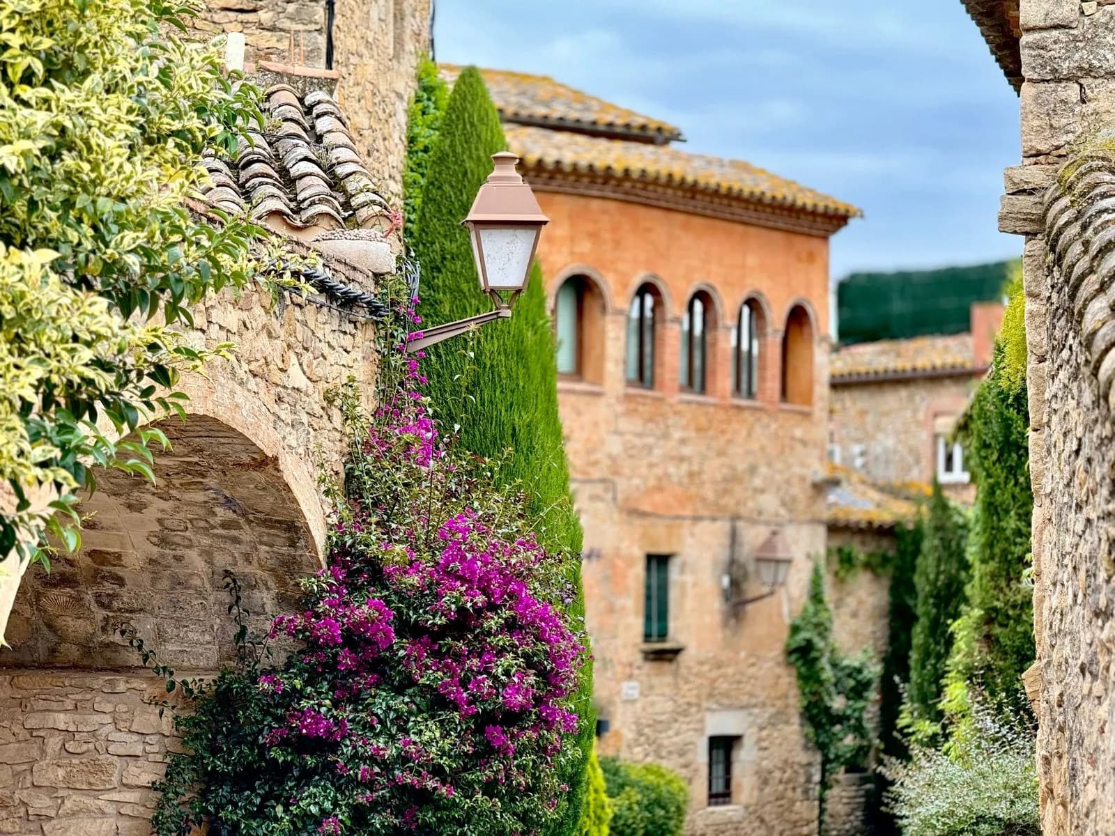 Stone archway with bougainvillea and lantern in historic town near Begur and La Bisbal.