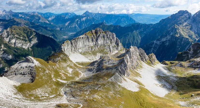 Rugged limestone mountain peaks with green slopes under a cloudy sky, Cima di Zita.