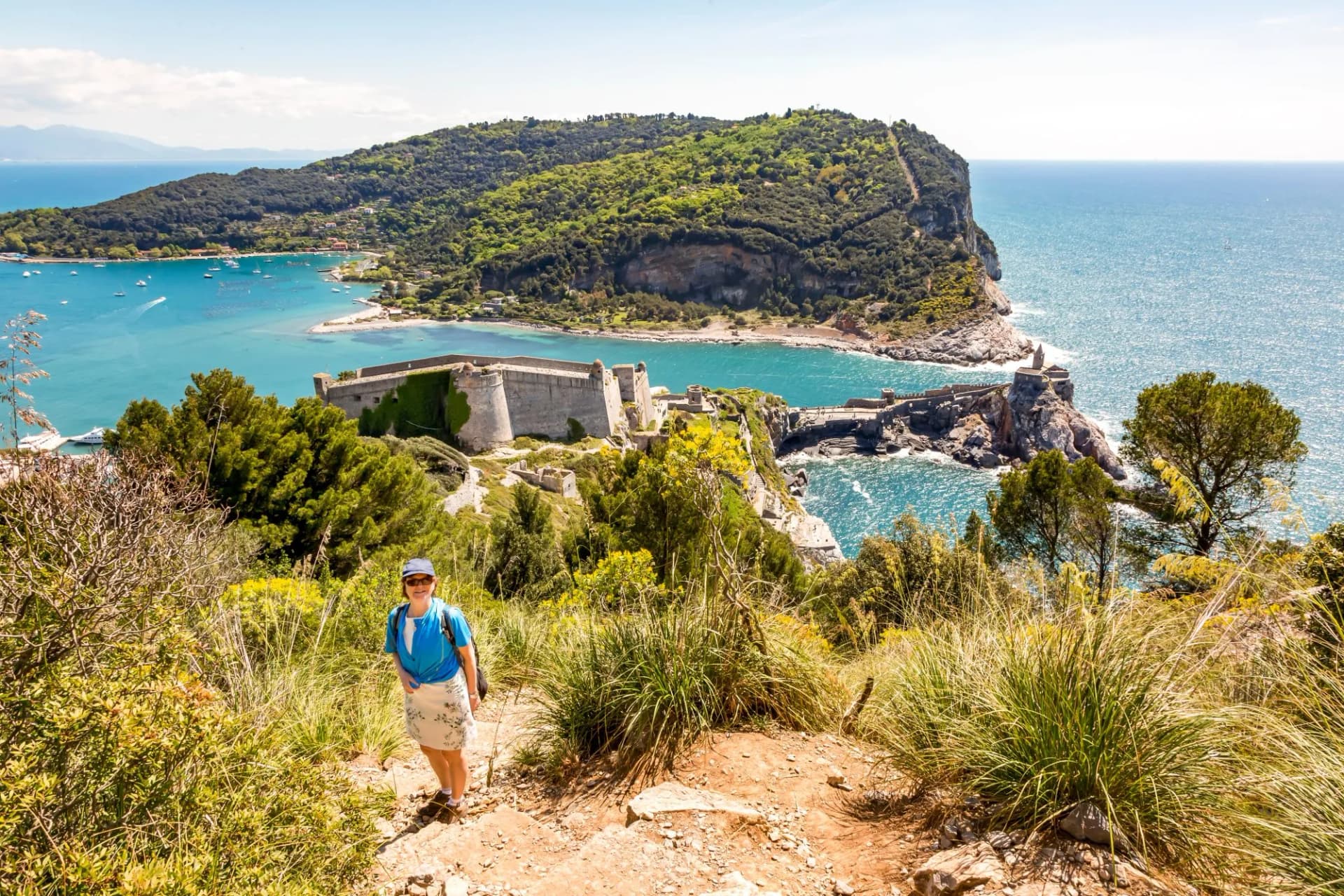 Hiking above Portovenere with view of fortified coastline and turquoise sea.