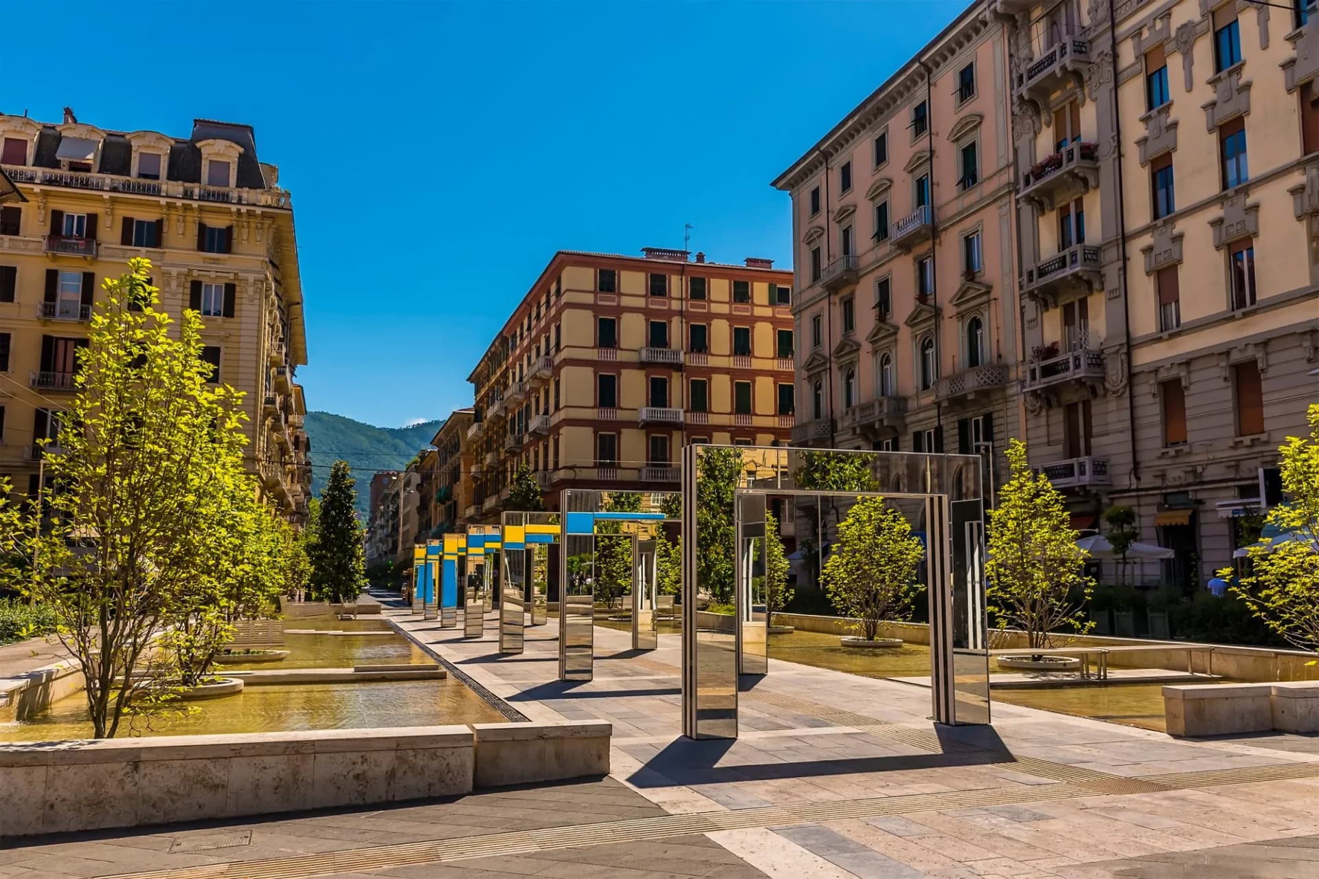 View across Piazza Giuseppe Verdi in La Spezia with modern mirrored art installations and water features.
